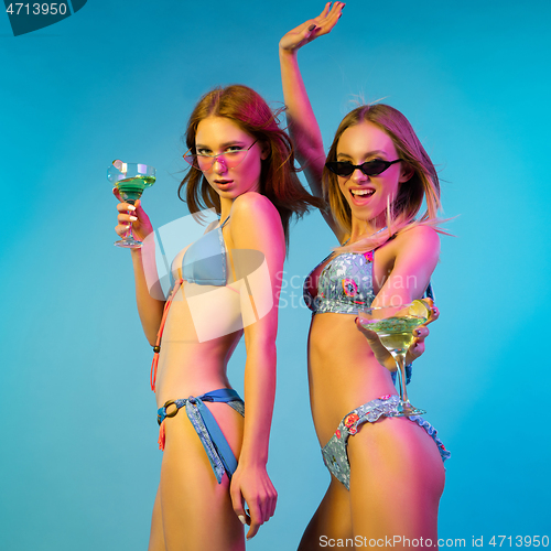 Image of Beautiful girls isolated on blue studio background in neon light