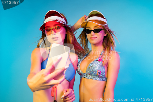 Image of Beautiful girls isolated on blue studio background in neon light