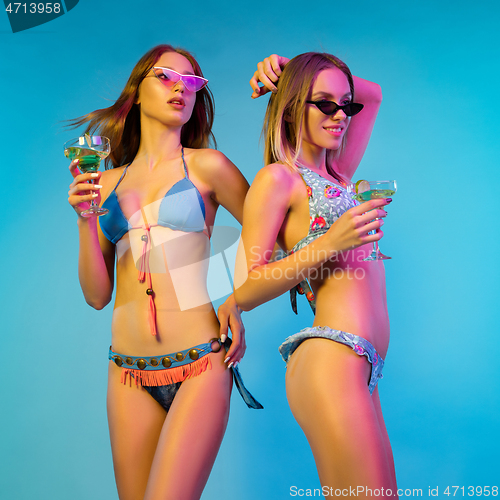 Image of Beautiful girls isolated on blue studio background in neon light
