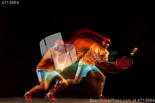 Image of One caucasian man playing tennis on black background