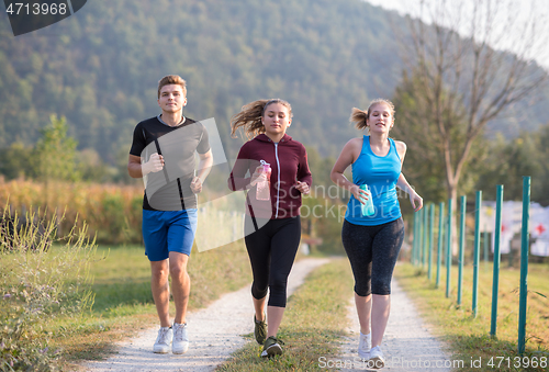 Image of young people jogging on country road