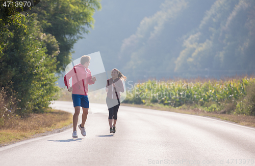Image of young couple jogging along a country road