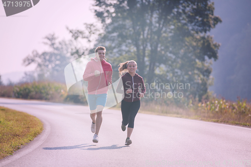 Image of young couple jogging along a country road