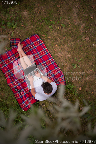 Image of top view of man using a laptop computer under the tree