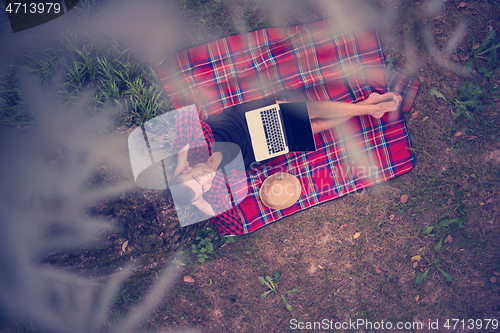 Image of top view of man using a laptop computer under the tree