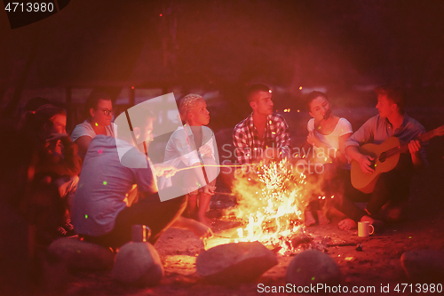 Image of young friends relaxing around campfire