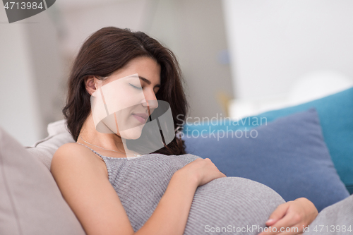 Image of pregnant woman sitting on sofa at home