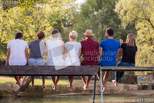 Image of rear view of friends enjoying watermelon while sitting on the wo