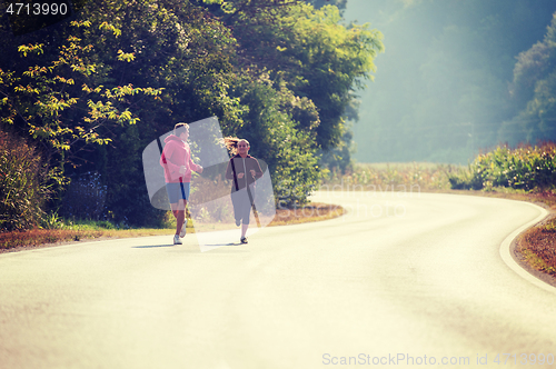 Image of young couple jogging along a country road