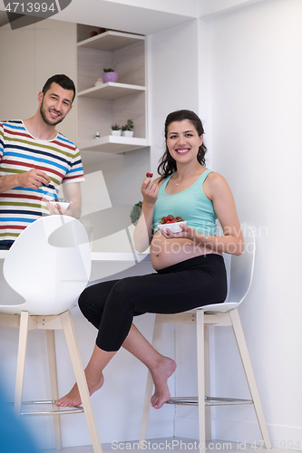 Image of couple eating fruit strawberries at kitchen