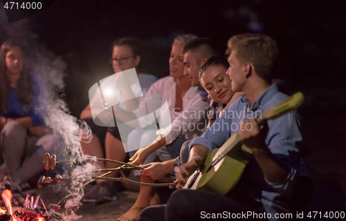 Image of young friends relaxing around campfire