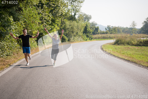 Image of young couple jogging along a country road