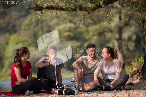 Image of friends smoking hookah on the river bank