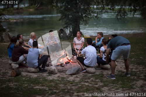 Image of young friends relaxing around campfire