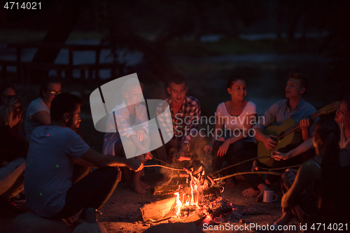 Image of young friends relaxing around campfire