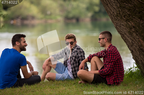 Image of men sitting on the bank of the river