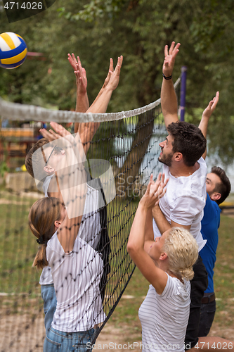 Image of group of young friends playing Beach volleyball