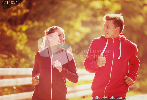 Image of young couple jogging along a country road