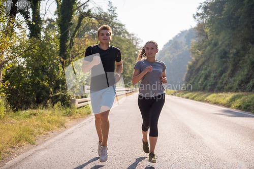 Image of young couple jogging along a country road