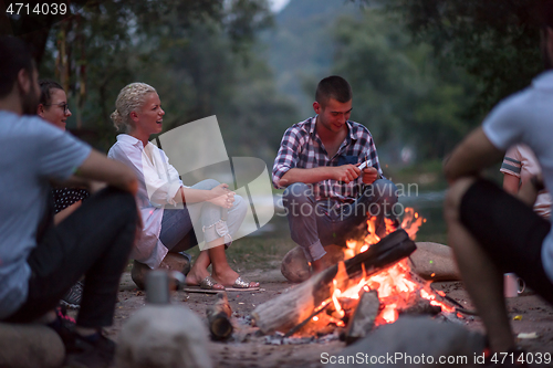 Image of young friends relaxing around campfire