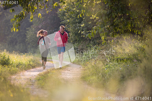 Image of young couple jogging along a country road