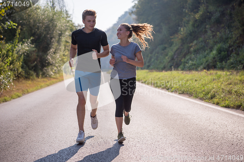 Image of young couple jogging along a country road