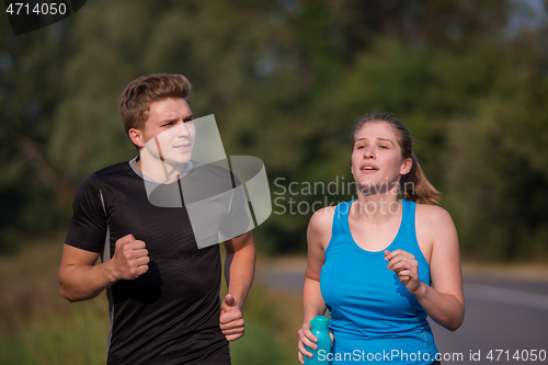 Image of young couple jogging along a country road