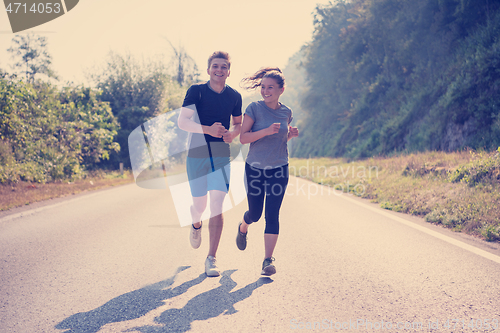 Image of young couple jogging along a country road