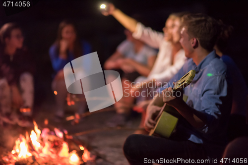 Image of young friends relaxing around campfire