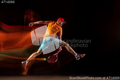 Image of One caucasian man playing tennis on black background