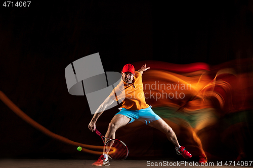 Image of One caucasian man playing tennis on black background