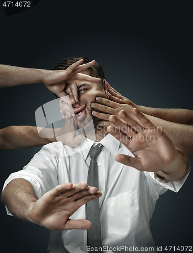 Image of A young man surrounded by hands like his own thoughts