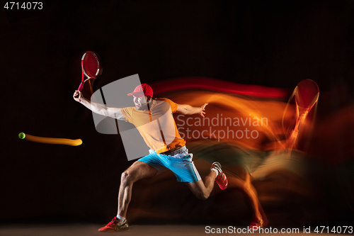 Image of One caucasian man playing tennis on black background