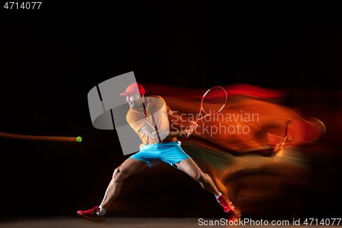 Image of One caucasian man playing tennis on black background