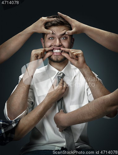 Image of A young man surrounded by hands like his own thoughts