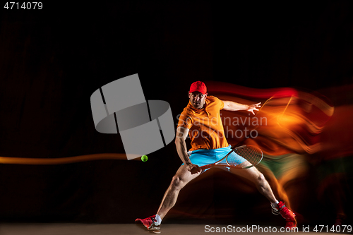 Image of One caucasian man playing tennis on black background