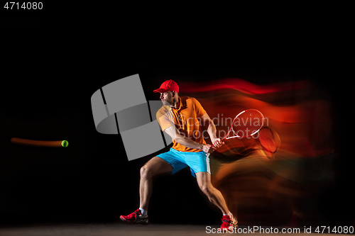 Image of One caucasian man playing tennis on black background