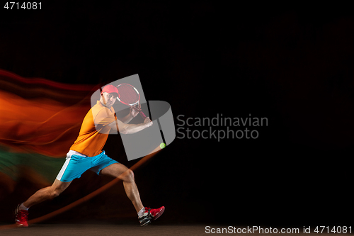 Image of One caucasian man playing tennis on black background