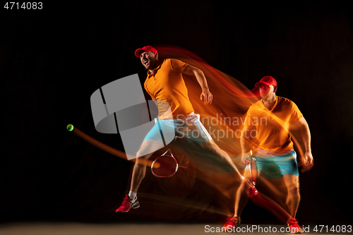 Image of One caucasian man playing tennis on black background
