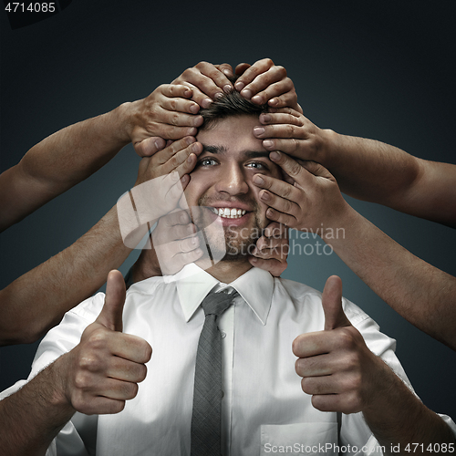 Image of A young man surrounded by hands like his own thoughts