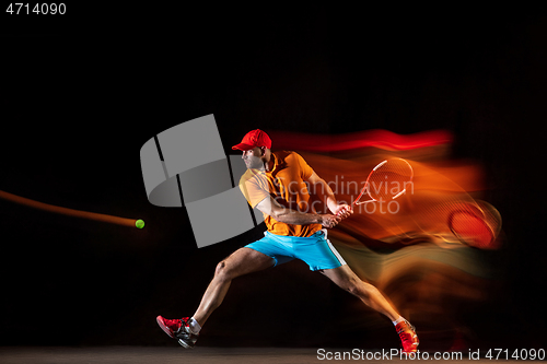 Image of One caucasian man playing tennis on black background