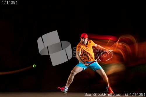 Image of One caucasian man playing tennis on black background