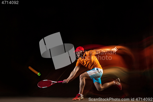 Image of One caucasian man playing tennis on black background