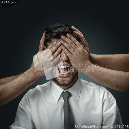 Image of A young man surrounded by hands like his own thoughts