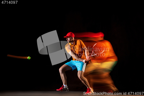 Image of One caucasian man playing tennis on black background