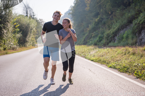 Image of young couple jogging along a country road
