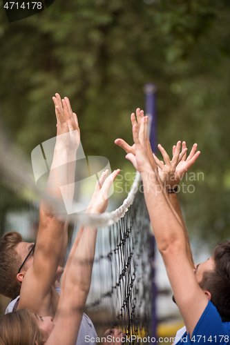 Image of group of young friends playing Beach volleyball