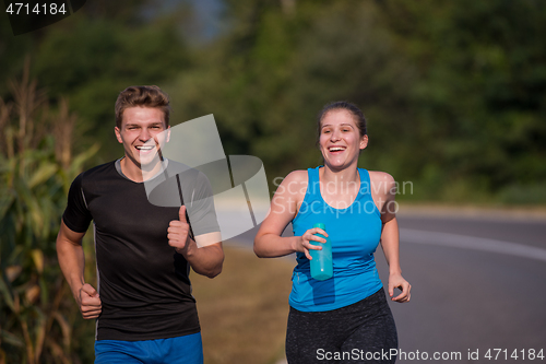 Image of young couple jogging along a country road