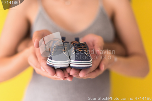 Image of couple holding newborn baby shoes