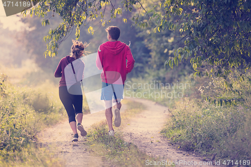 Image of young couple jogging along a country road